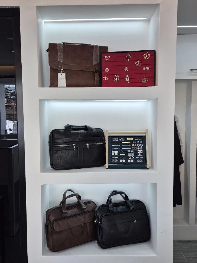 Maletines exhibidos en tramos iluminados, mostrando también algunos broches, pisacorbatas y gemelos.